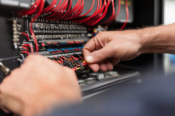 Electrician managing chaotic wiring in control panel