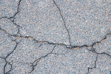 A closeup photograph showcasing a cracked asphalt road surface