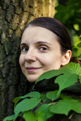 Portrait of mid-aged brunette with natural beauty among the leaves of trees