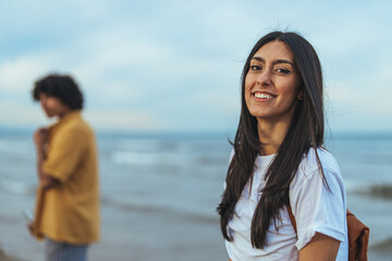 Smiling Woman on Beach with Blurred Companion in the Distance