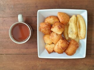Bolang baling, Odading, fried bread in cubes or blocks, with a light brown crunchy outer skin and sprinkled with sesame seeds with cup of tea on wooden table