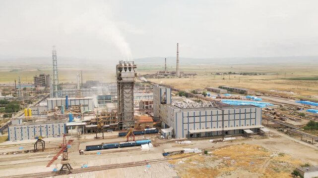 Aerial view of Rustavi Azot factory complex in Georgia showing production buildings, storage tanks, tall chimneys emitting smoke, and extensive industrial infrastructure