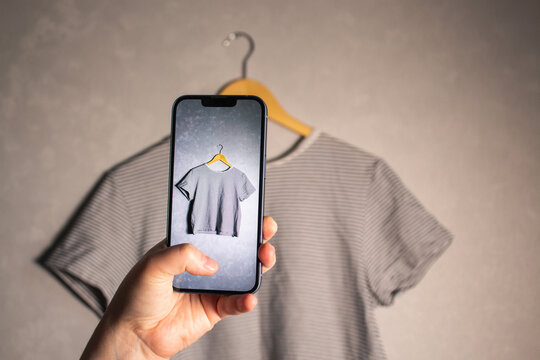 Close up of hands holding smartphone camera capturing old clothes items for online resale resources. Image for second hand concept.