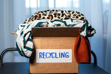 Cardboard box full of clothes labeled Recycling. Concept of sustainable fashion and responsible...