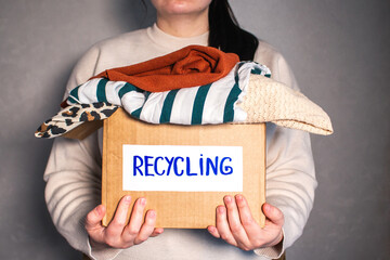 Woman prepared cardboard box full of used outfits for recycling. Responsible disposal and...