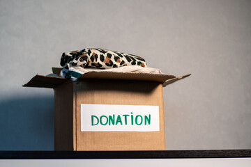 Cardboard box full of clothing ready for donation. Modern eco friendly habits and conscious...