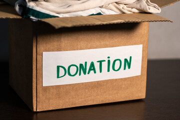 Cardboard box full of clothing ready for donation. Modern eco friendly habits and conscious...