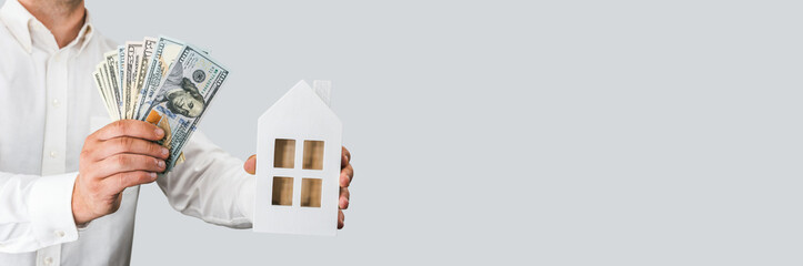 Hand Holding Money and House Model for Real Estate