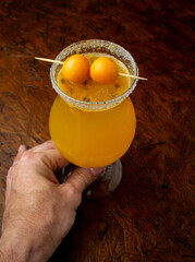 Tropical Passion Fruit Margarita cocktail with a sugar rim and goldenberry garnish, a refreshing...
