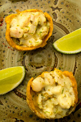 Platter of fresh seafood ceviche appetizers in fried plantain cups (patacones), a gourmet Latin American dish with lime, photographed as a flat lay on a wooden table for a restaurant menu.
