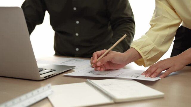 Architect and engineer compare hand writing draft with construction blueprint detail display in laptop for accurate design, measurement tool and plan on table at modern office. Closeup. Delineation.