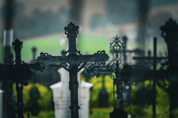 Artistic photo of rapprochement of cast iron crosses at the cemetery in the rain, with a fucked up...
