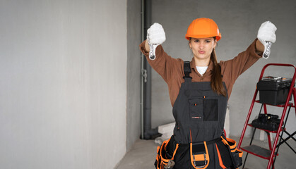 Female builder or repairman wearing overalls and hardhat showing thumb down with two hands