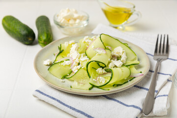 Cucumber salad on a wooden background.Homemade salad with fresh vegetables, cucumber, tomato, sweet pepper and lettuce in a plate.Vegetarian spring salad.Vegetarian diet.Healthy eating.Space for text