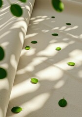 Creamy fabric backdrop with scattered green leaves in dappled sunlight