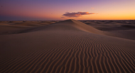 Saharan Serenity Sand Dunes at Sunset A Textured Landscape of Rippling Sands under a Vibrant Sky with Hues of Orange Purple and Brown in a Desert Scene