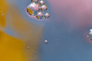 abstract background water droplets, ring and crystal shapes reflecting pink, orange and blue wet surface, copy space