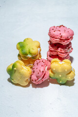 French macaron or macaroon cookies in strawberry pink and yellow green lemon, diagonal row, spring and summer edition, high angle view, vertical shot, close up, copy space