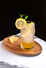 Iced Lemon Drink in Textured Glass with Citrus Garnish on Wooden Tray