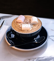 Cozy Cinnamon Latte with Marshmallows in Black Cup on Marble Table