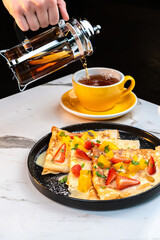 Fruit Crepe with Lemon Sauce and Berries, Served with Hot Tea Being Poured by Hand