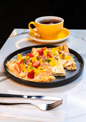 Fruit Crepes with Lemon Sauce and Fresh Berries Served with Tea in a Yellow Cup