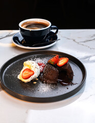 Sliced Molten Chocolate Lava Cake with Strawberries and Vanilla Ice Cream beside Hot Americano
