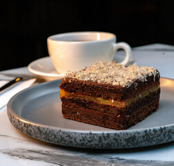 Chocolate Caramel Layer Cake Slice with White Chocolate Shavings and Hot Tea
