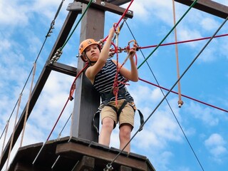 a teenage boy in outdoor rope park passing obstacle course. Active summer holidays