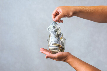 Living Off Savings: Hand Holding Money Jar for Financial Independence.