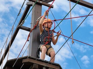 a teenage boy in outdoor rope park passing obstacle course. Active summer holidays