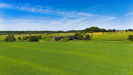 Fototapeta premium Old Abandoned Concrete Bridge in Rural Sāti, Latvia - Historic Structure in Green Countryside - Drone View