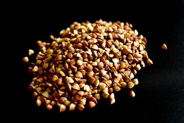 Buckwheat grains lie on a black background.