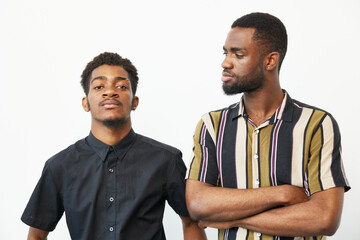 Two black men pose confidently in stylish shirts, exuding camaraderie and individuality, showcasing...