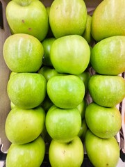 Fresh Green Apples Stacked in Rows at a Market or Grocery Display