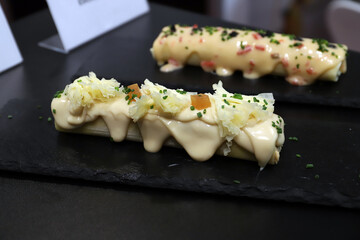canelones gourmet con crema y salsa emplatados en una tabla de piedra de pizarra