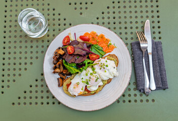 Gourmet breakfast plate with poached eggs on avocado toast, smoked salmon, and fresh salad.Top view.Healthy and balanced brunch with avocado toast, poached eggs, smoked salmon, and side of mushrooms