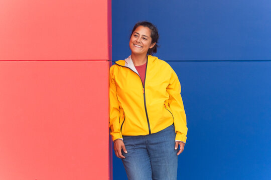 Woman in yellow raincoat against colorful wall