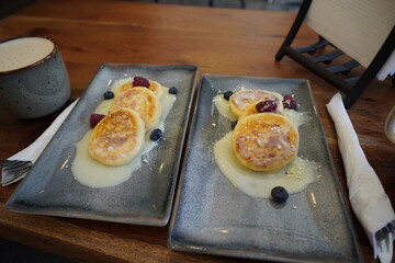 Cup of coffee with cottage cheese pancakes,served in a cozy café.Warm atmosphere with soft natural lighting and stylish table setting.
