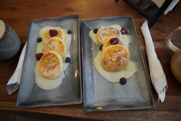 Cup of coffee with cottage cheese pancakes,served in a cozy café.Warm atmosphere with soft natural lighting and stylish table setting.
