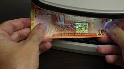 Examination of Sri Lanka rupee (LKR) cash money with UV counterfeit detector. Concept of authenticity check, fight against counterfeiting of banknotes, anti fraud measures in Sri Lanka. Close up view.