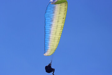 Paraglider flying in a blue sky	