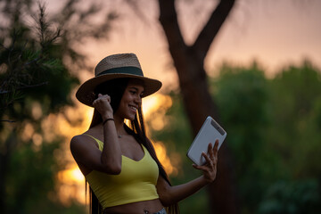 Latin tourist using tablet in pine forest at sunset