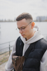 a handsome man of European appearance stands on the embankment in a big city against the background of a river