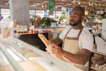 Bakery worker wrapping bread in eco-friendly store