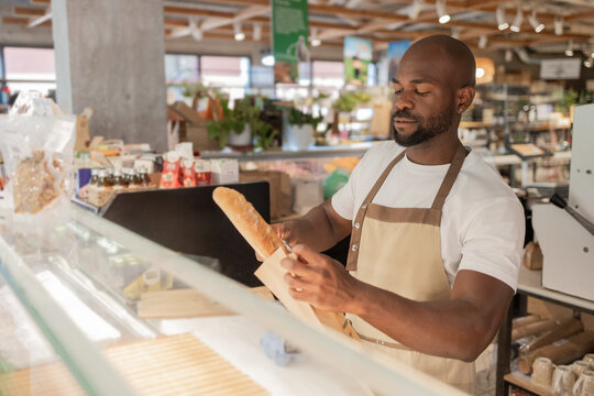 Bakery worker wrapping bread in eco-friendly store