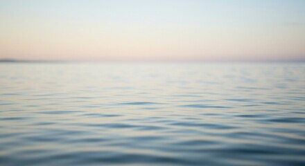 Obraz premium Gentle ocean waves with a serene, pastel-colored sky during the golden hour. Peaceful vibes