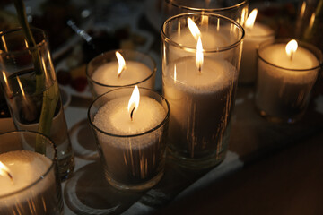 Numerous candles in glass holders emit warm, soft light, creating a serene and peaceful atmosphere. The arrangement suggests a setting for relaxation, meditation, or special events.