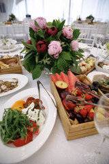 A beautifully arranged table with vibrant flowers and a selection of fresh fruits accompanied by...