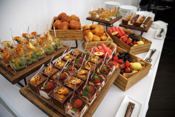  Tiramisu cups topped with fresh raspberries and colorful crumbs served on a wooden platter. Small spoons are ready for enjoyment, highlighting the dessert's inviting presentation.